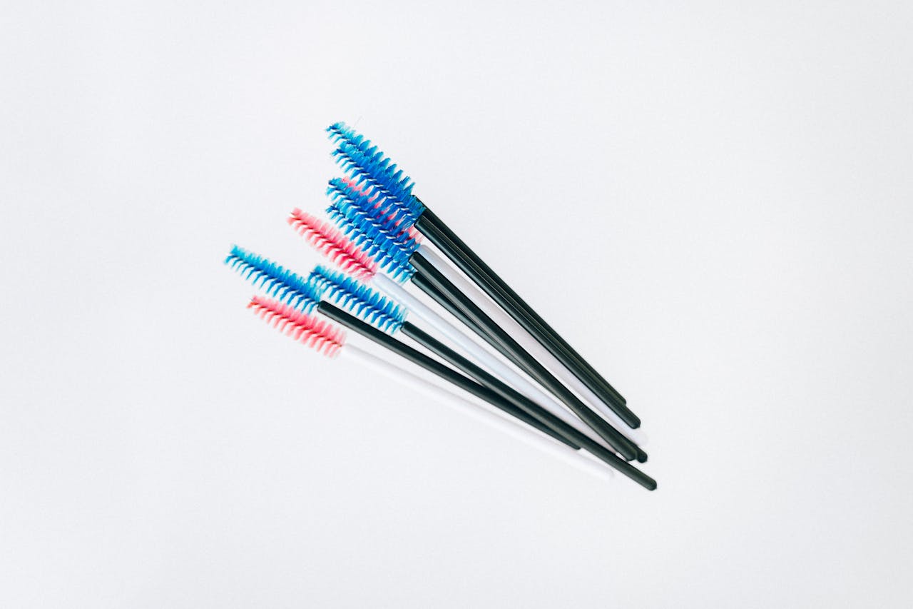 A set of colorful mascara applicator brushes arranged on a white background.